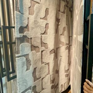Taupe Interlocking Geometric Rug displayed on a carpet showroom rack, model CR-018