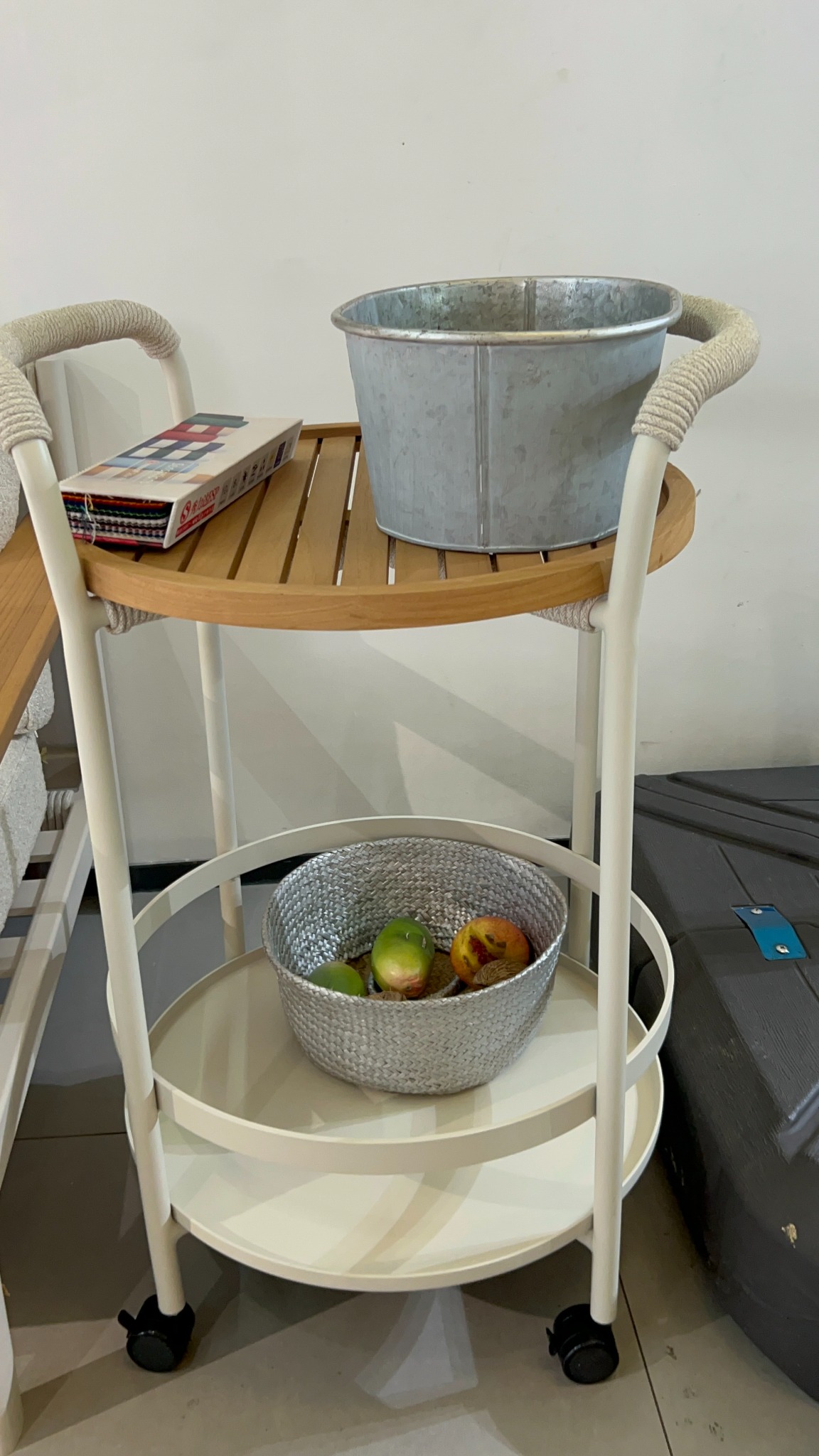 Round two-tier serving trolley with slatted wood-tone upper tray, light frame, rope-wrapped handles and caster wheels